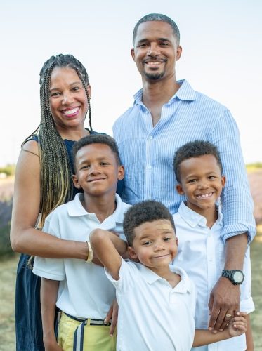 The Curtis family poses together outdoors near a lavender field at sunset.