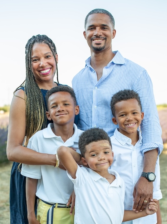 The Curtis family poses together outdoors near a lavender field at sunset.