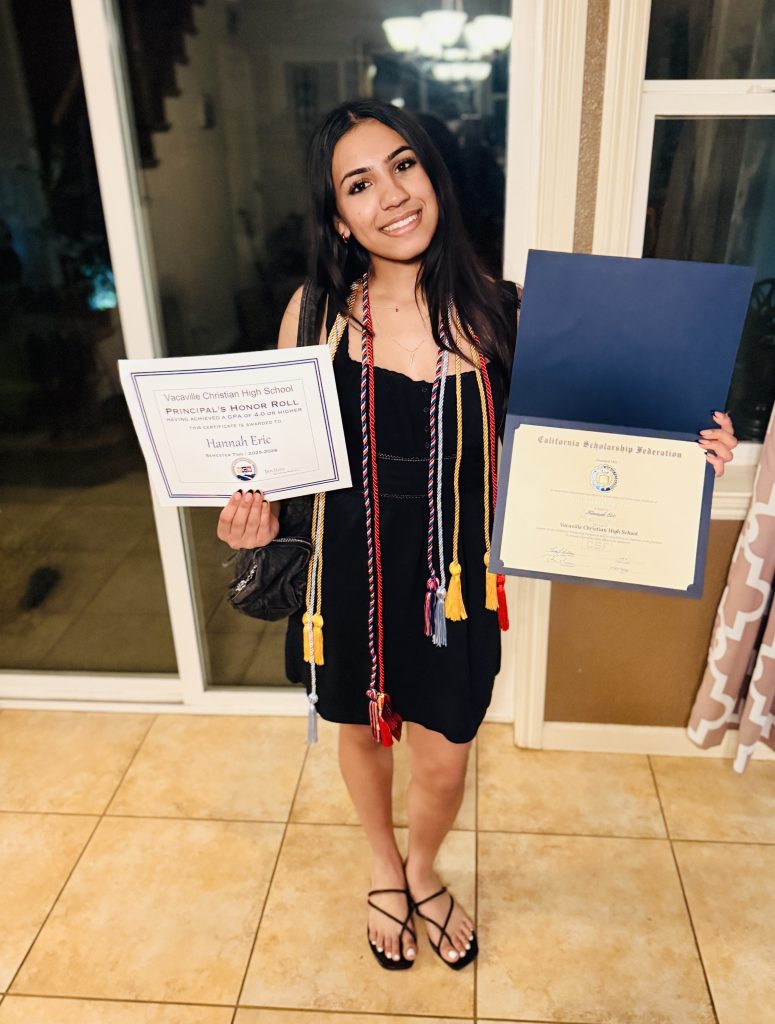 Vacaville Christian High School graduate smiling while holding Honor Roll and California Scholarship Federation certificates, wearing graduation honor cords.