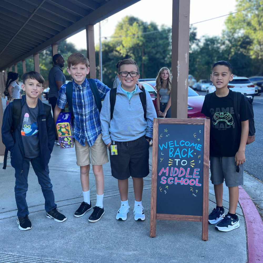 Middle school students pose beside a Welcome Back sign on the first day of school at Vacaville Christian School.
