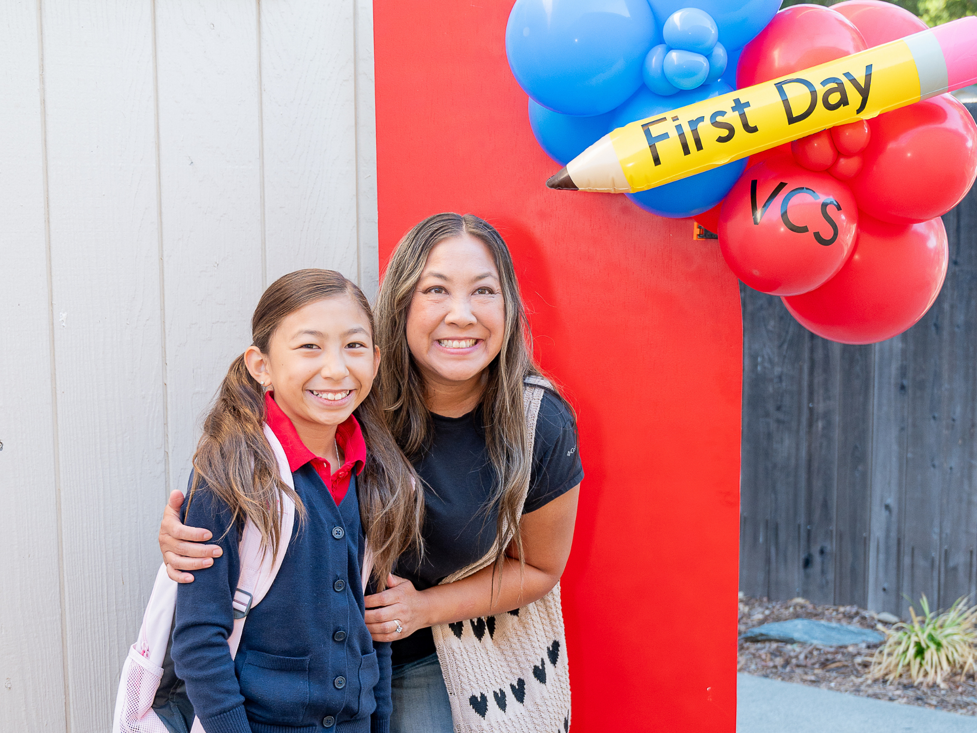 Parent and elementary student posing at Vacaville Christian School's First Day of School display during back-to-school orientation.
